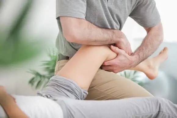 EinePhysiotherapeutinoderPhysiotherapeut behandelt eine Sportverletzung am Knie.
