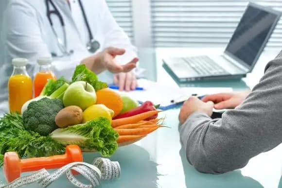 Arzt im Gespräch für Ernährungsberatung, frisches Obst und Gemüse am Tisch.