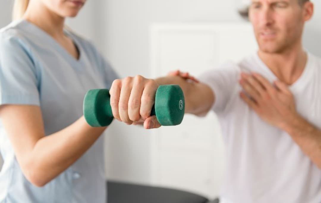 Sportphysiotherapeut hilft einem Patienten bei einer Übung mit einer Hantel in der Hand