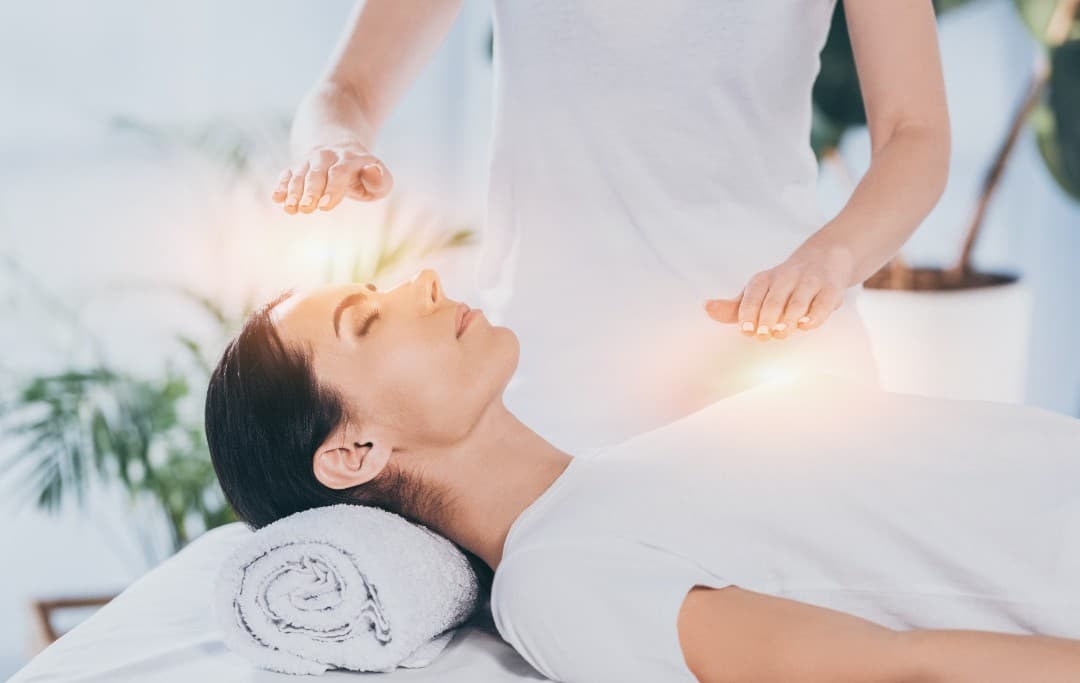 Energetikerin führt Reiki Massage mit Ihren Händen an einer liegenden Patientin durch